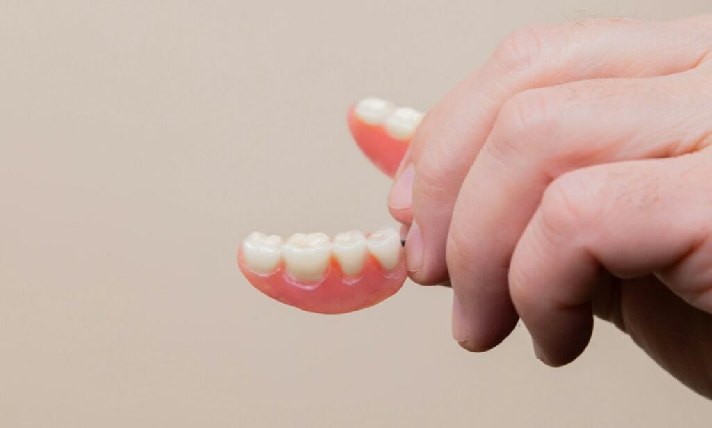 Homme âgé tenant sa prothèse dentaire amovible (dentier)